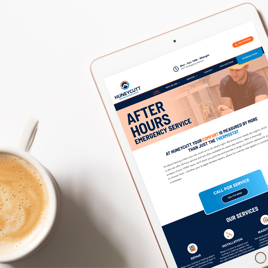 Tablet displaying Huneycutt HVAC custom website design next to coffee mug.